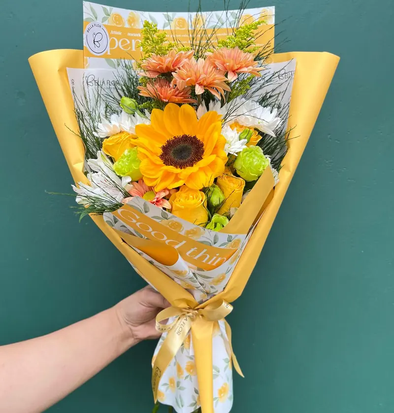 Ramo amarillo con un girasol, en papel amarillo, sobre una pared verde