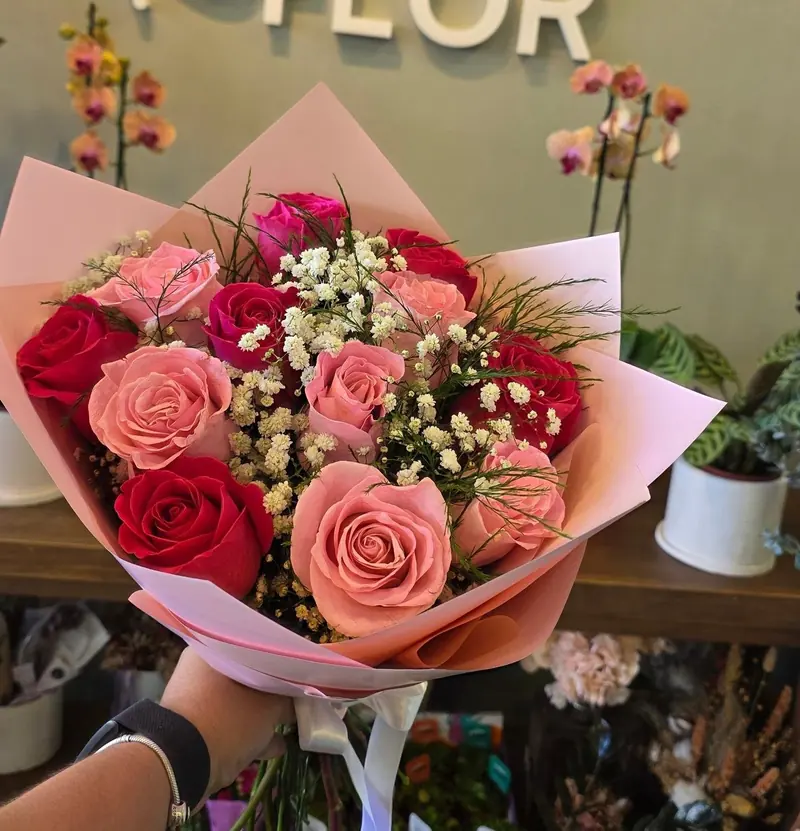 Ramo de doce rosas rosadas y rojas con paniculata, en papel rosa