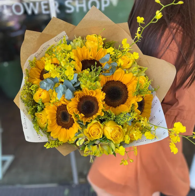 Ramo de girasoles y rosas amarillas en papel kraft